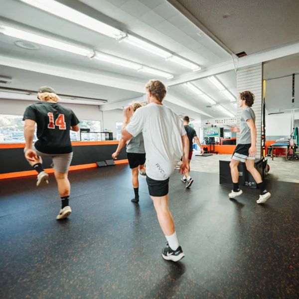 Young athletes running an agility drill together in the gym
